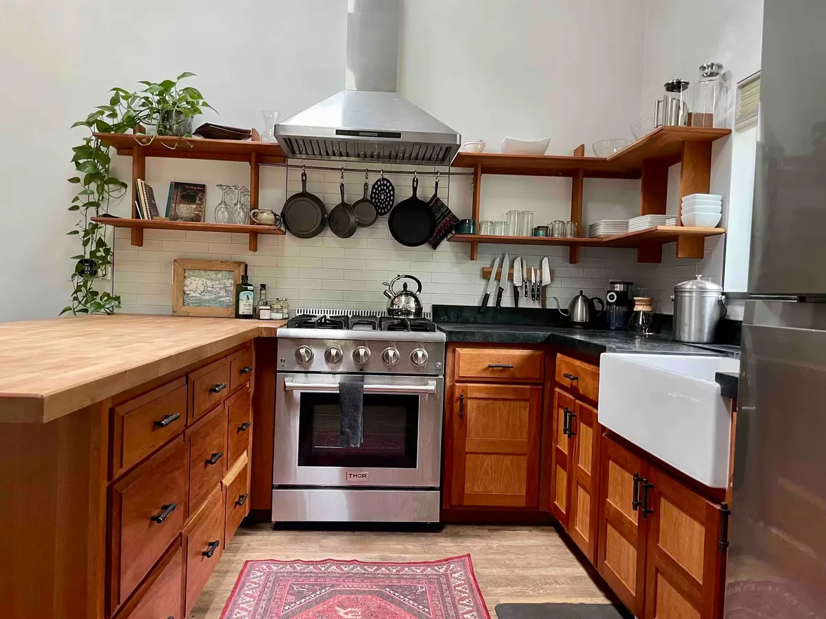Kitchen with cherry cabinets, butcher-block and soapstone counters, a farmhouse sink, open shelves, and a steel range