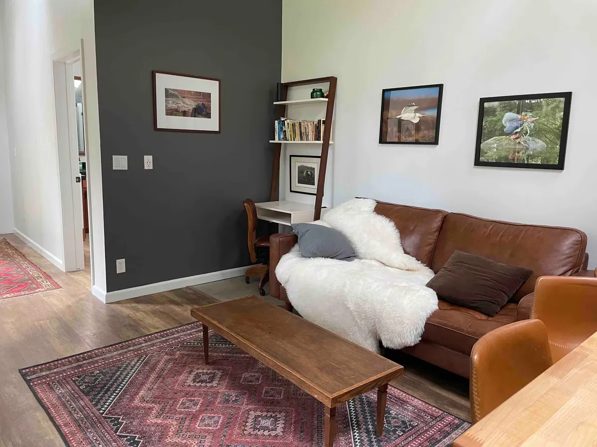 Living room with a leather sofa, sheepskin throw, wood coffee table, and framed bird photographs