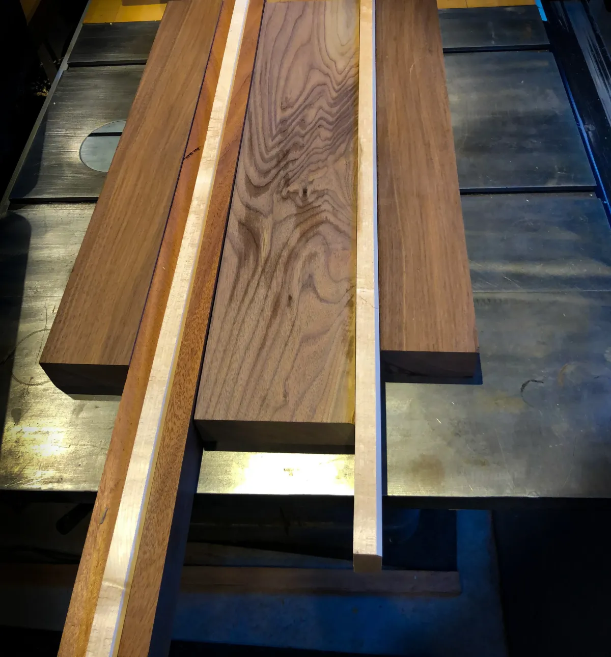 Walnut and maple boards stacked on a workbench